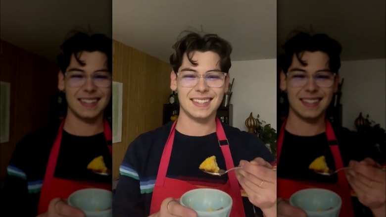 Jeremy Scheck wearing red apron holding forkful of food