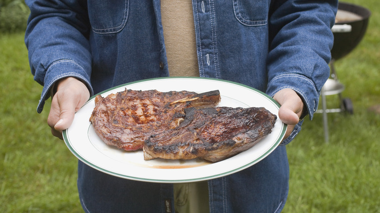 man holding plate of steak