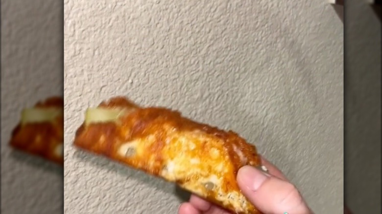 hand holding fried cheesy pickle