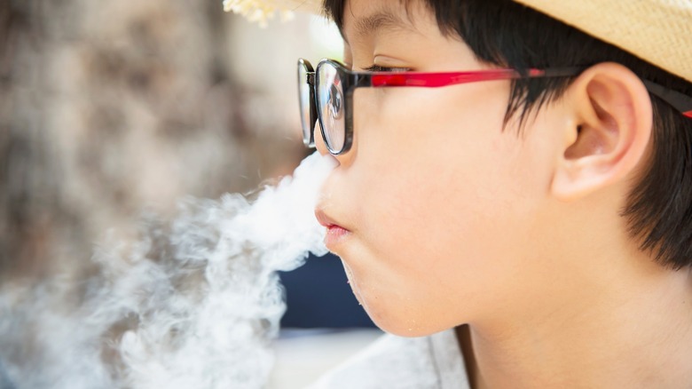 Child wearing glasses exhaling vapor