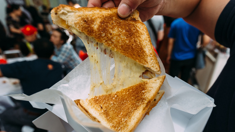 Person pulling apart grilled cheese sandwich