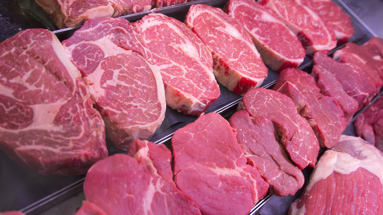 Row of raw steaks in meat case 