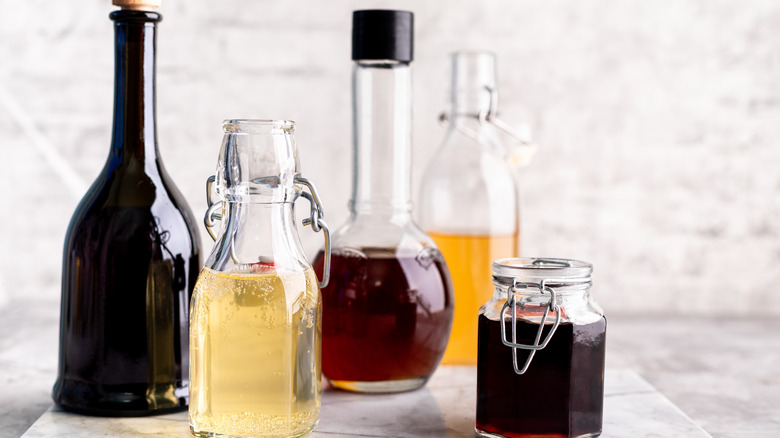 five different bottles of vinegar with white counter and wall background