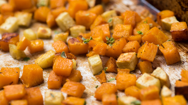 roasted squash and parsnip chunks with fresh thyme on unlined metal baking sheet