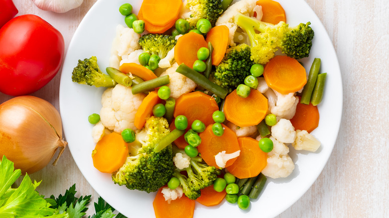 white plate of boiled carrots, broccoli, green beans, cauliflower, and peas