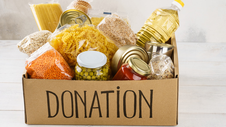 carboard box labeled donation and filled with pasta, lentils, cans, and other nonperishable food