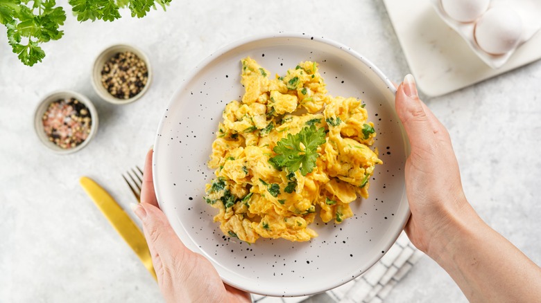 Plate of scrambled eggs topped with herbs