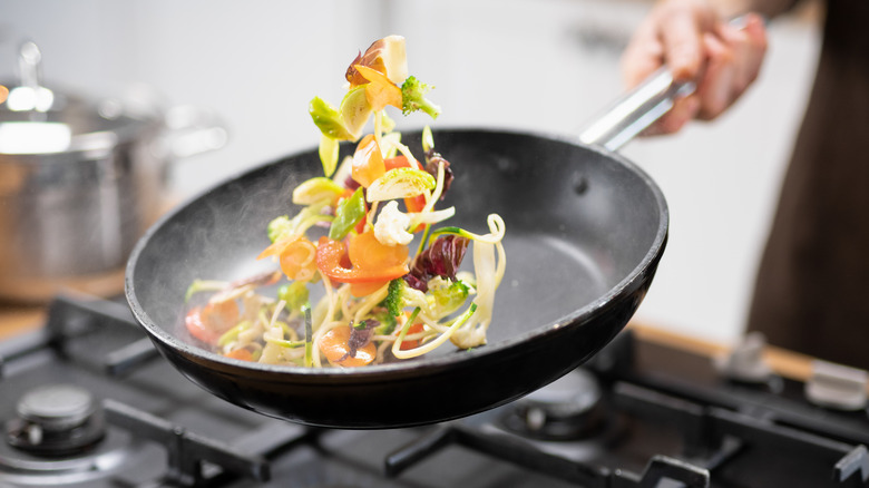 Vegetables being tossed in skillet