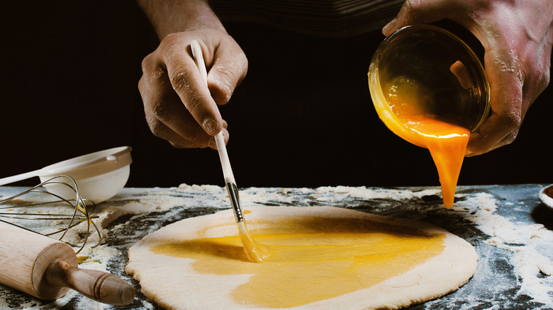 brushing egg wash on dough