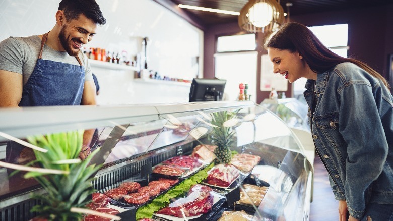 butcher helping customer choose meat