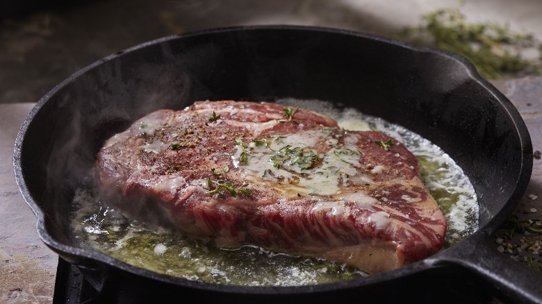 steak cooking in cast iron pan