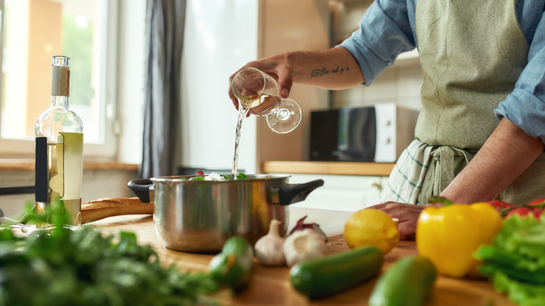 man pouring wine into pan