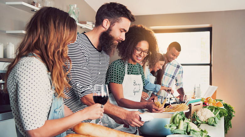 friends cooking pasta with wine