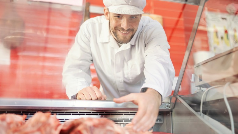 Smiling butcher selecting meat