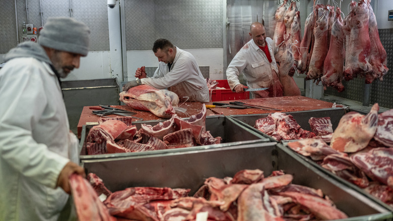 Butchers preparing meat in back room of shop