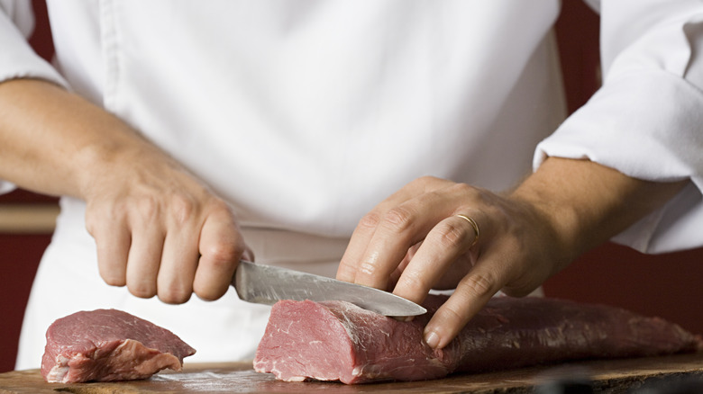 Butcher slicing pork tenderloin