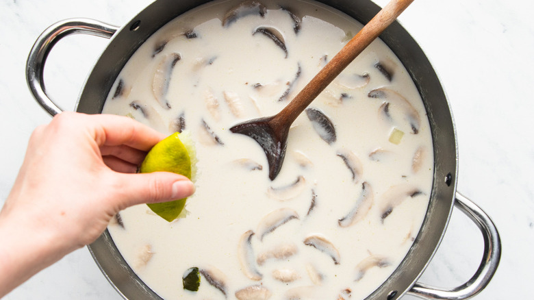 hand squeezing lime into soup