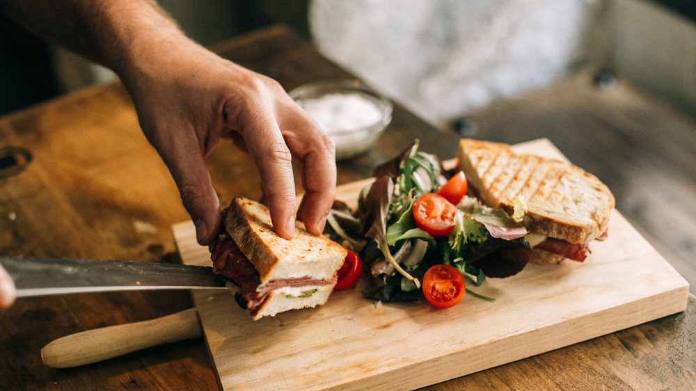 Person preparing a sandwich on cutting board