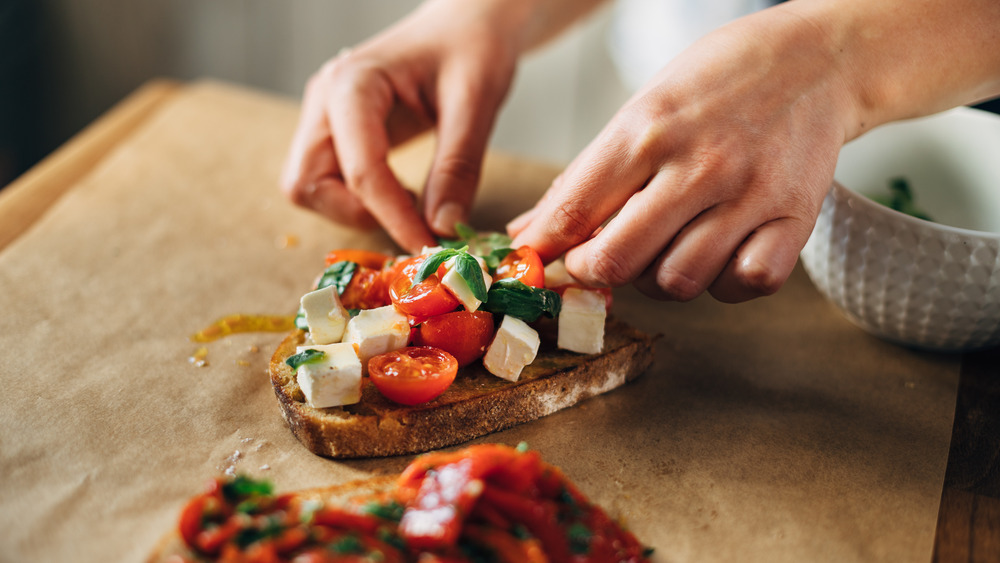 Person putting tomatoes on bread