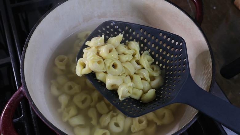 scooping tortellini from pot