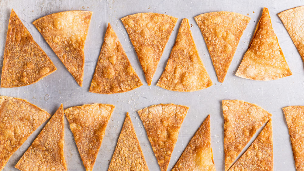 Baked tortilla chips on a baking sheet.