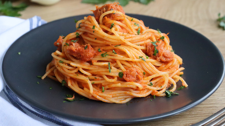 Plate of spaghetti covered in sauce and herbs