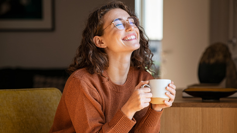 A smiling woman holding a mug of tea in her hands