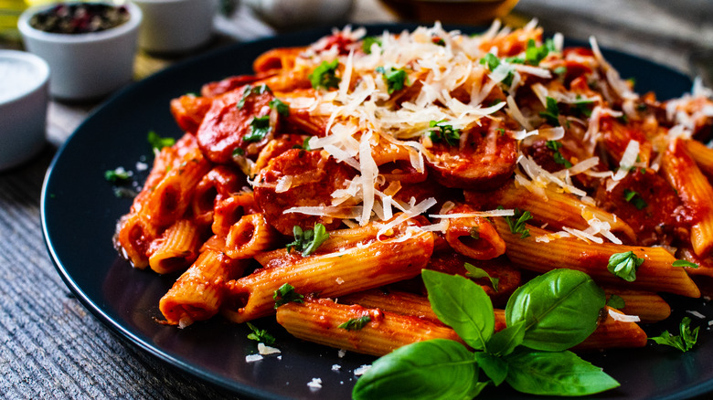 A plate of pasta with marinara sauce topped with cheese and garnish