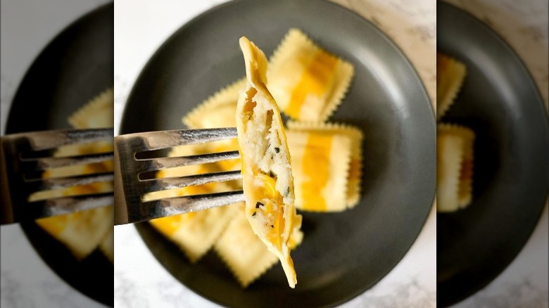 Fork holding ravioli over bowl