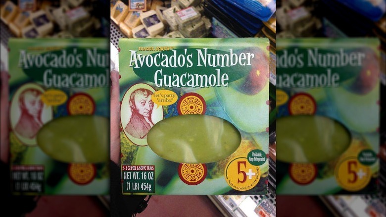 Someone holding a container of guacamole from Trader Joe's