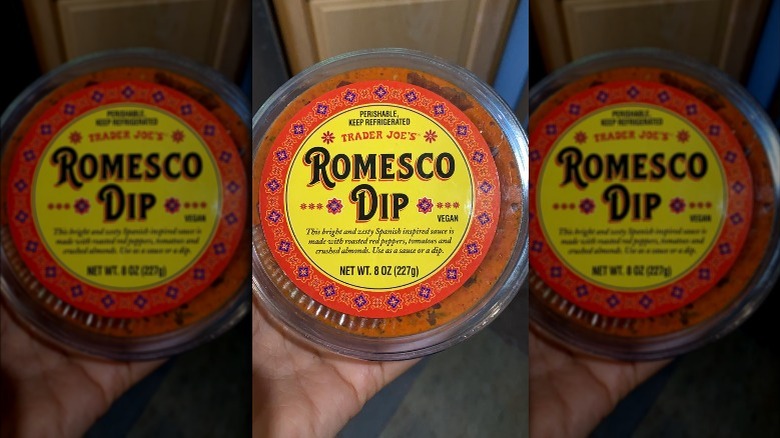 Someone holds a container of Romesco dip from Trader Joe's