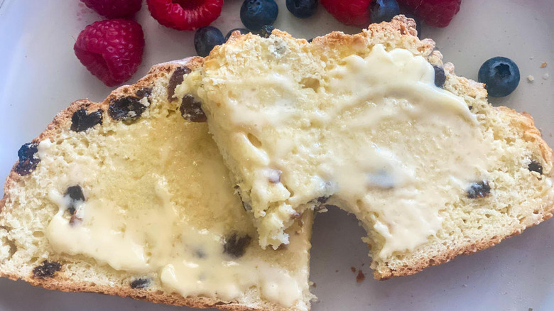 buttered slices of traditional Irish soda bread on a white plate with fresh blueberries and red raspberries