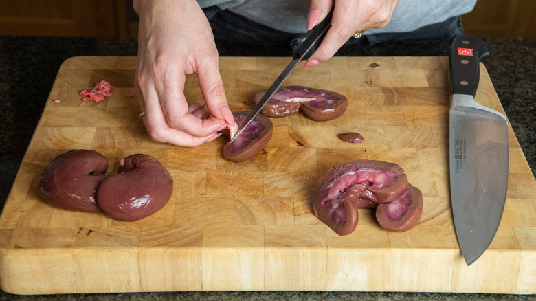 Chopping lamb kidneys on cutting board