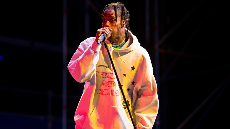 Travis Scott sings on stage in hoodie