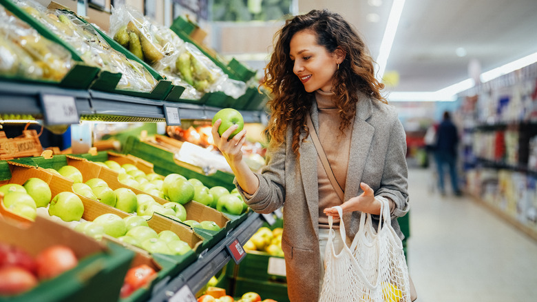 person feeling apple in grocery store