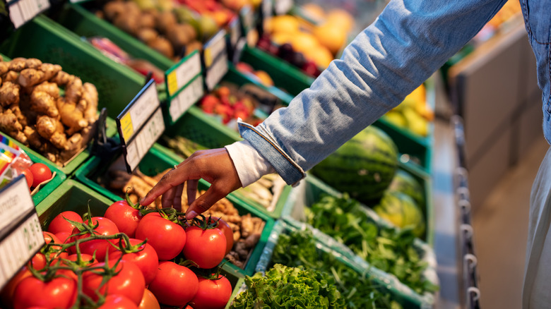 person picking up produce in grocery store