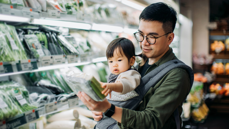 person with baby reading label on produce