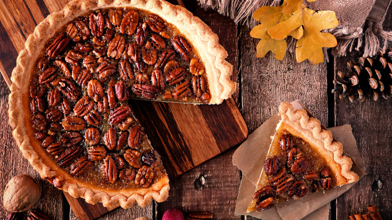 Fresh pecan pie sliced on wooden plank