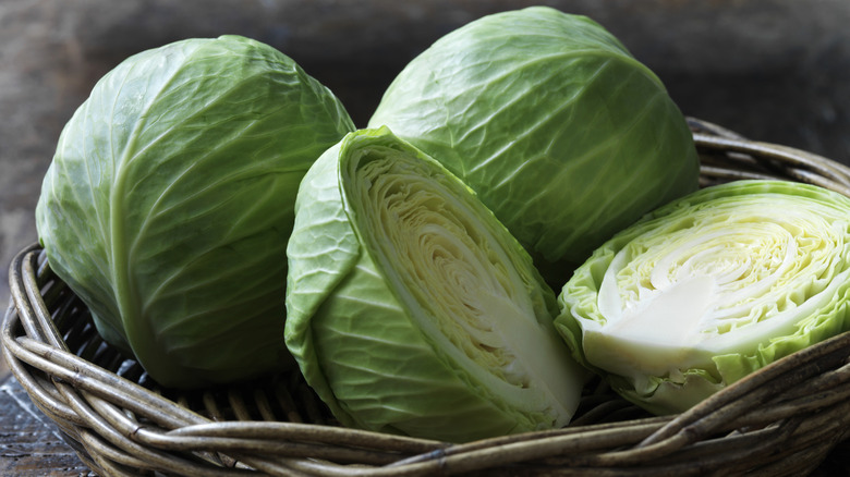 Cut heads of cabbage in basket with grayish background