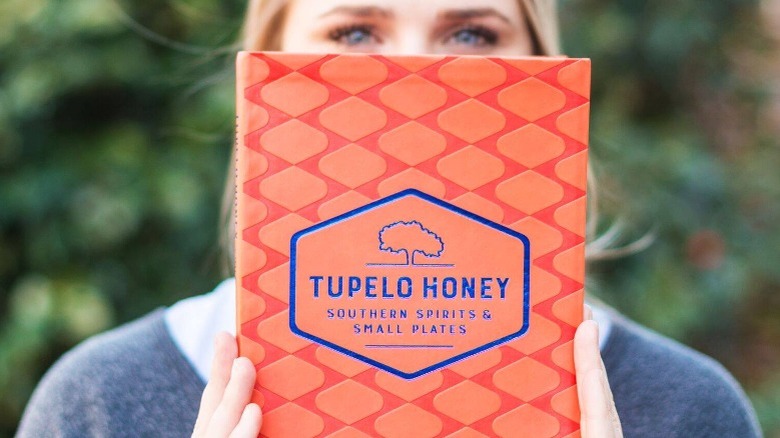 Woman holding up Tupelo Honey cookbook