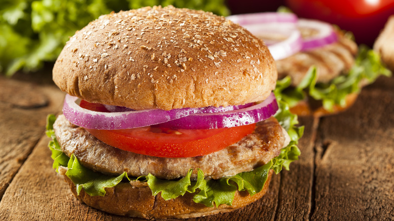 Burger with toppings and salad in the background