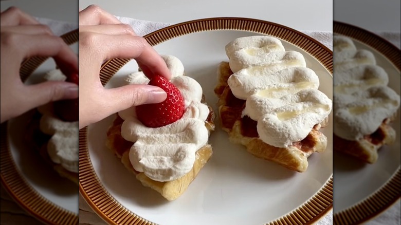 putting strawberry and cream on crescent roll waffles