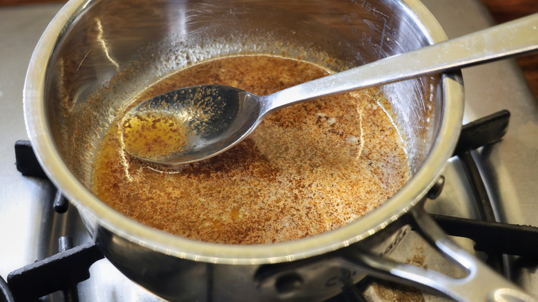 hot butter sauce in small saucepan with spoon in it