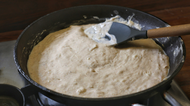 skillet full of melted cheese dip with large spoon