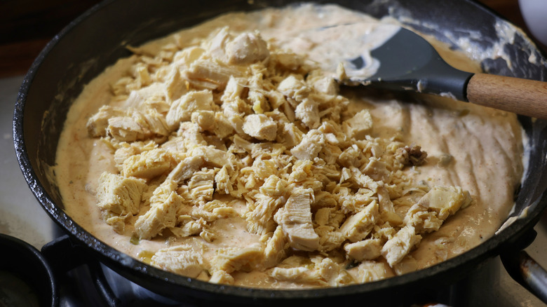 skillet of melted cheese dip with chopped chicken on top