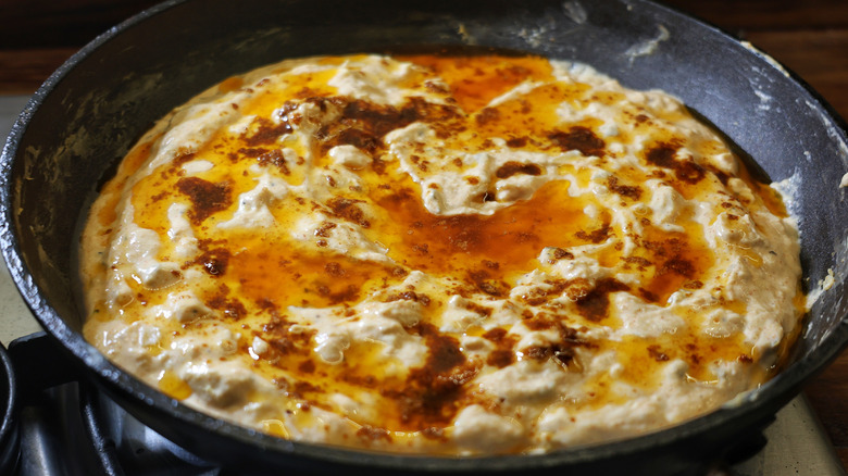 skillet of melted chicken dip with hot butter sauce on top