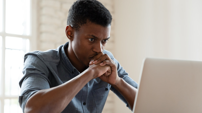 A guy at a computer looks vexed