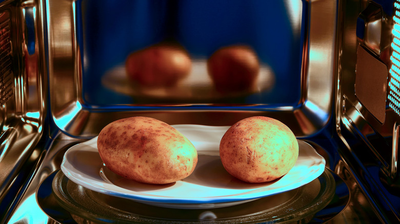 Two potatoes on a dish in a microwave