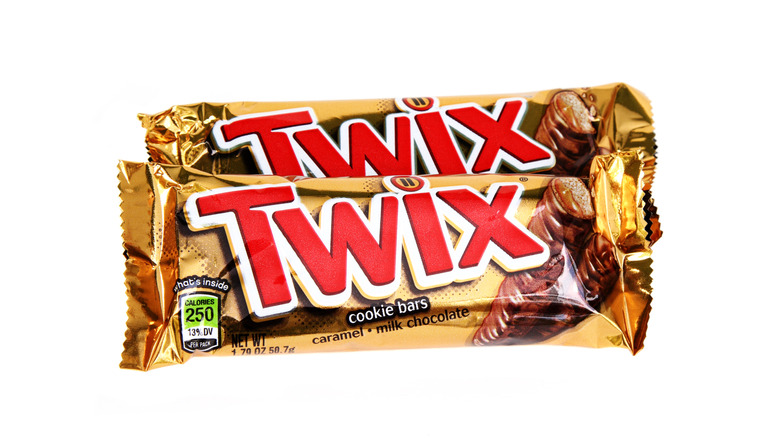 Hand holding Twix package over grass