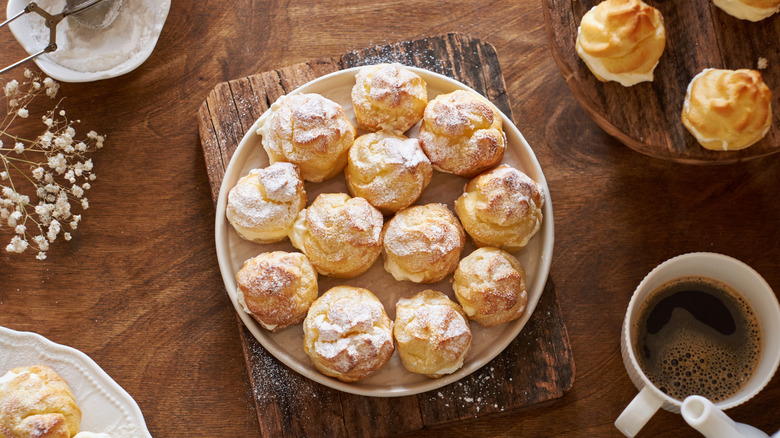 Profiteroles with powdered sugar on wooden board